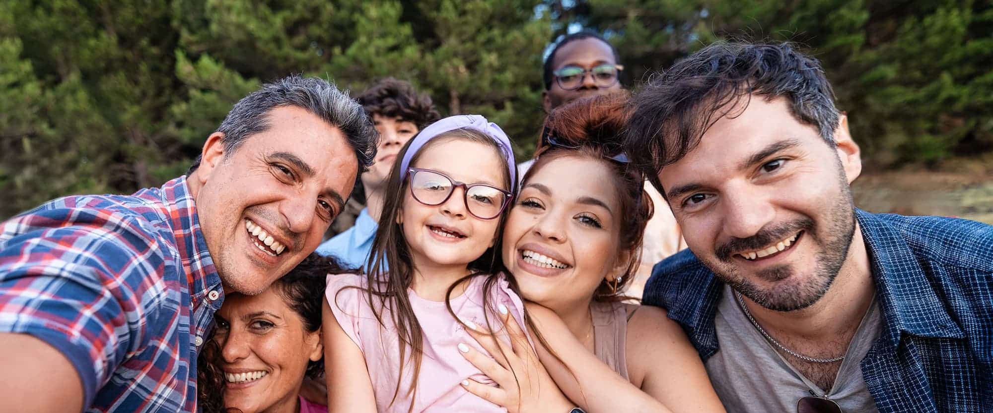 Happy multigenerational family taking a group selfie outdoors.