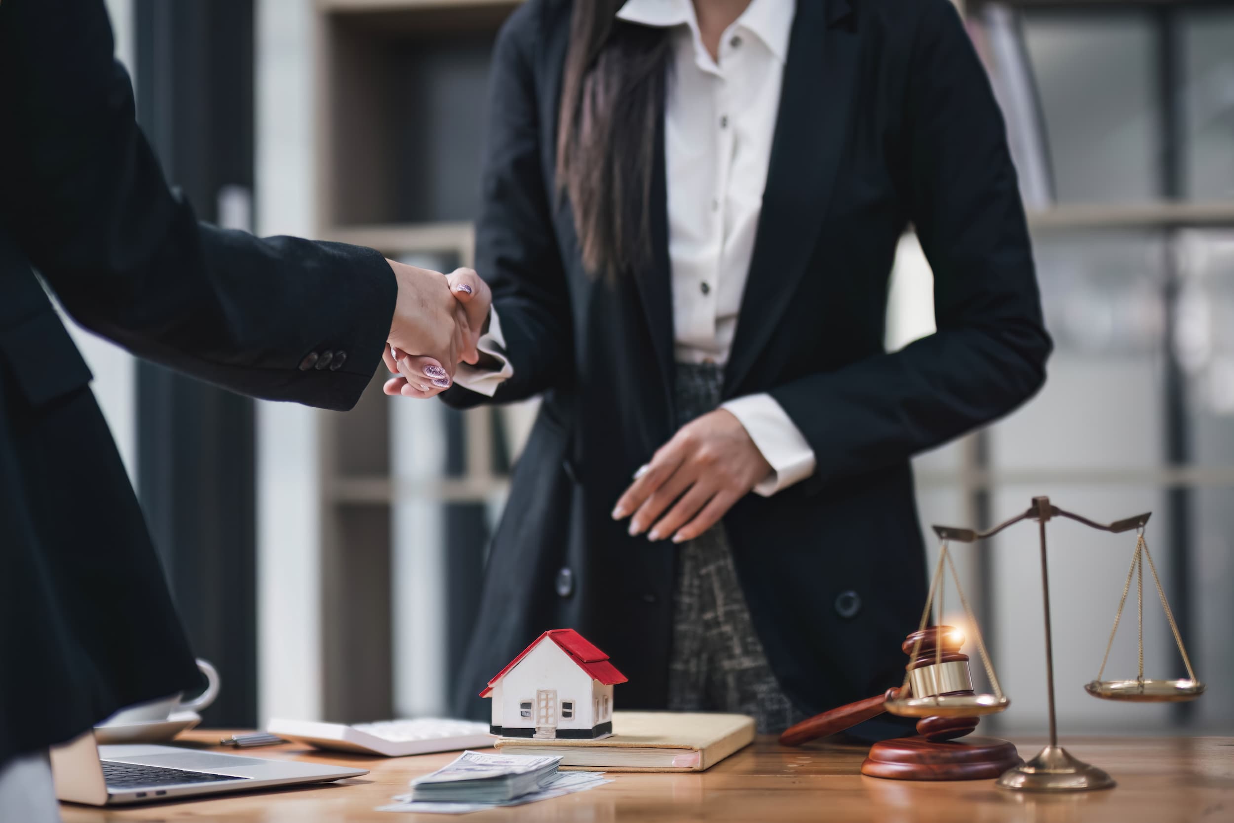 Lawyer shaking hands with client over property agreement in office.