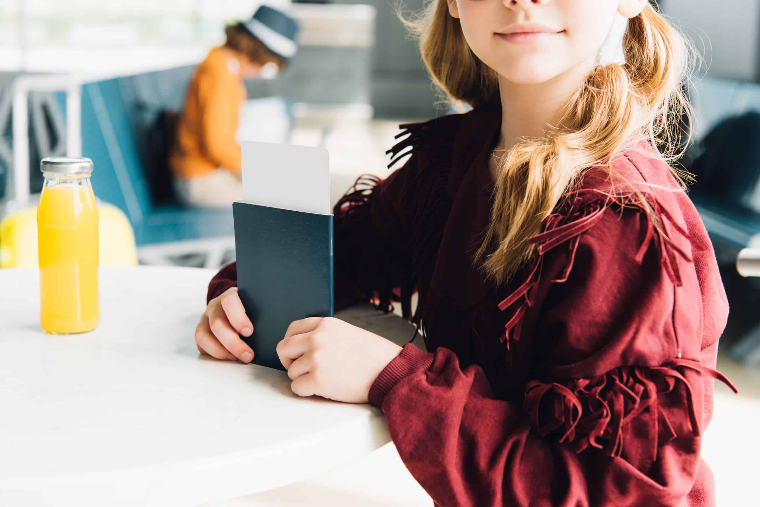 Young girl holding passport and boarding pass at airport.